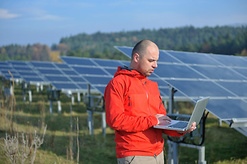 Image showing engineer using laptop at solar panels plant field