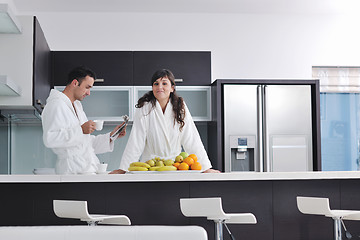 Image showing Happy couple reading the newspaper in the kitchen at breakfast