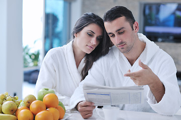 Image showing Happy couple reading the newspaper in the kitchen at breakfast