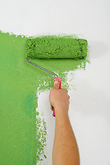 Image showing handsome young man paint white wall in color