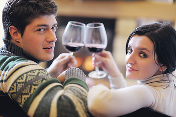 Image showing Young romantic couple sitting and relaxing in front of fireplace