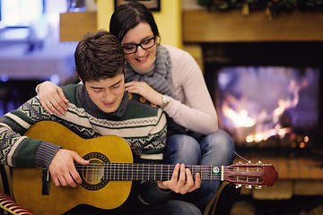 Image showing Young romantic couple sitting on sofa in front of fireplace at h