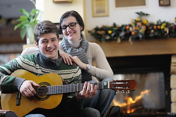 Image showing Young romantic couple sitting on sofa in front of fireplace at h