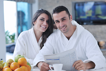 Image showing Happy couple reading the newspaper in the kitchen at breakfast