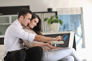 Image showing joyful couple relax and work on laptop computer at modern home