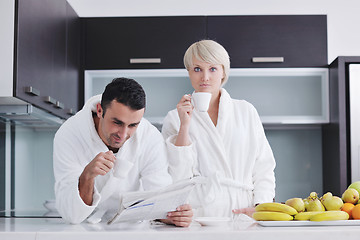 Image showing Happy couple reading the newspaper in the kitchen at breakfast