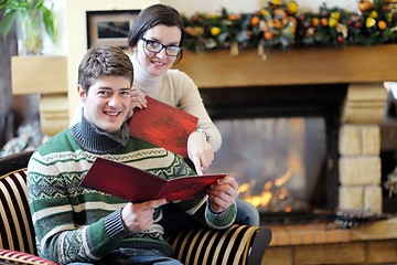 Image showing Young romantic couple relax on sofa in front of fireplace at hom