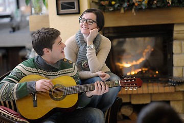 Image showing Young romantic couple sitting on sofa in front of fireplace at h