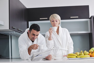 Image showing Happy couple reading the newspaper in the kitchen at breakfast