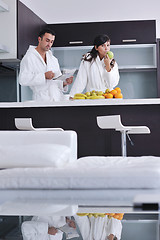 Image showing Happy couple reading the newspaper in the kitchen at breakfast