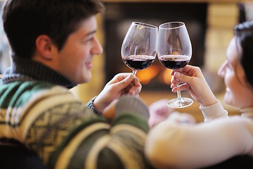 Image showing Young romantic couple sitting on sofa in front of fireplace at h