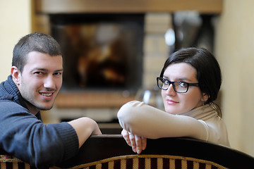 Image showing Young romantic couple sitting and relaxing in front of fireplace