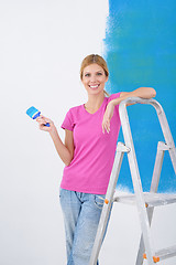 Image showing happy smiling woman painting interior of house