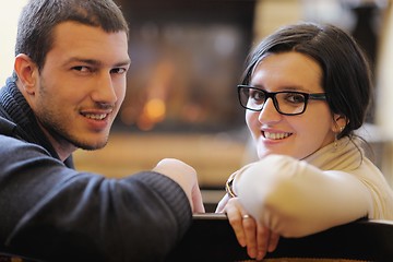Image showing Young romantic couple relax on sofa in front of fireplace at hom