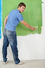 Image showing handsome young man paint white wall in color