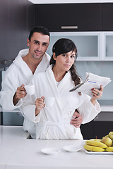 Image showing Happy couple reading the newspaper in the kitchen at breakfast