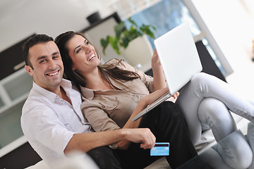 Image showing joyful couple relax and work on laptop computer at modern home