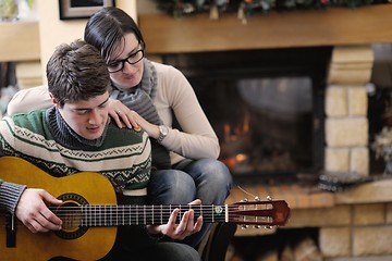 Image showing Young romantic couple sitting on sofa in front of fireplace at h