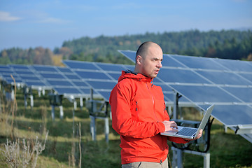 Image showing engineer using laptop at solar panels plant field