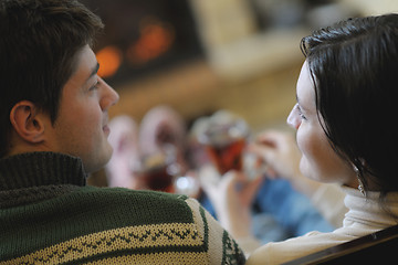 Image showing Young romantic couple sitting and relaxing in front of fireplace