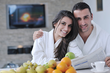 Image showing Happy couple reading the newspaper in the kitchen at breakfast