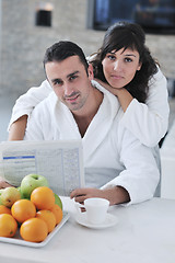 Image showing Happy couple reading the newspaper in the kitchen at breakfast