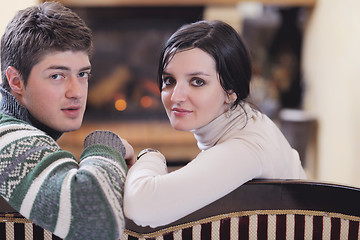 Image showing Young romantic couple sitting and relaxing in front of fireplace