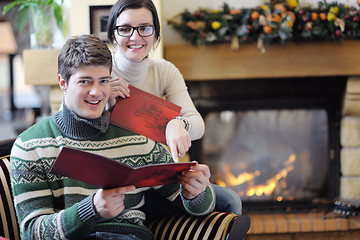 Image showing Young romantic couple sitting and relaxing in front of fireplace