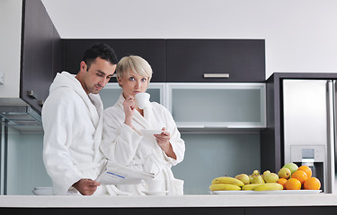 Image showing Happy couple reading the newspaper in the kitchen at breakfast