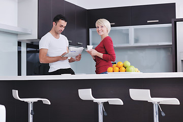 Image showing Happy couple reading the newspaper in the kitchen at breakfast