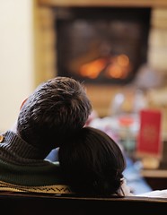 Image showing Young romantic couple sitting on sofa in front of fireplace at h