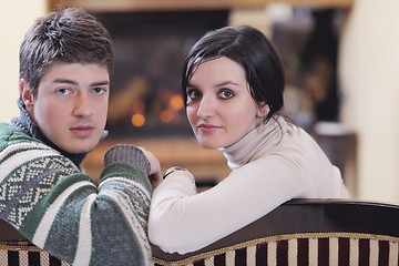 Image showing Young romantic couple sitting and relaxing in front of fireplace