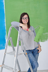 Image showing happy smiling woman painting interior of house