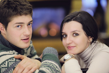 Image showing Young romantic couple sitting and relaxing in front of fireplace