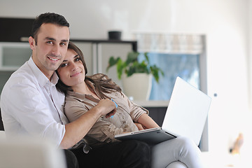 Image showing joyful couple relax and work on laptop computer at modern home