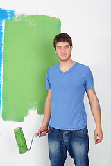 Image showing handsome young man paint white wall in color