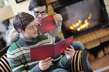 Image showing Young romantic couple sitting and relaxing in front of fireplace