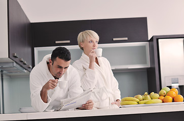 Image showing Happy couple reading the newspaper in the kitchen at breakfast