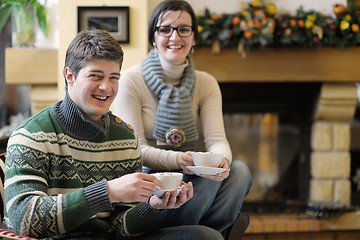 Image showing Young romantic couple sitting on sofa in front of fireplace at h