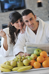 Image showing Happy couple reading the newspaper in the kitchen at breakfast