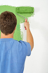 Image showing handsome young man paint white wall in color