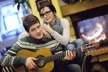 Image showing Young romantic couple sitting and relaxing in front of fireplace