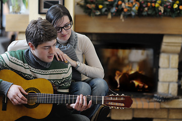 Image showing Young romantic couple sitting and relaxing in front of fireplace