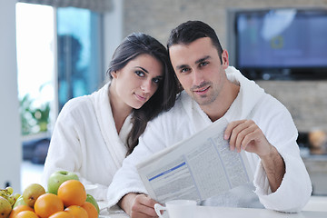 Image showing Happy couple reading the newspaper in the kitchen at breakfast