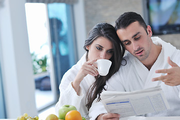 Image showing Happy couple reading the newspaper in the kitchen at breakfast