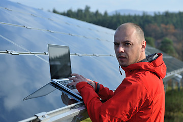 Image showing engineer using laptop at solar panels plant field