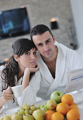 Image showing Happy couple reading the newspaper in the kitchen at breakfast