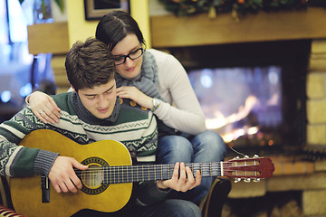 Image showing Young romantic couple sitting and relaxing in front of fireplace