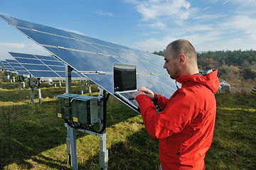 Image showing engineer using laptop at solar panels plant field