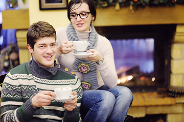 Image showing Young romantic couple sitting and relaxing in front of fireplace